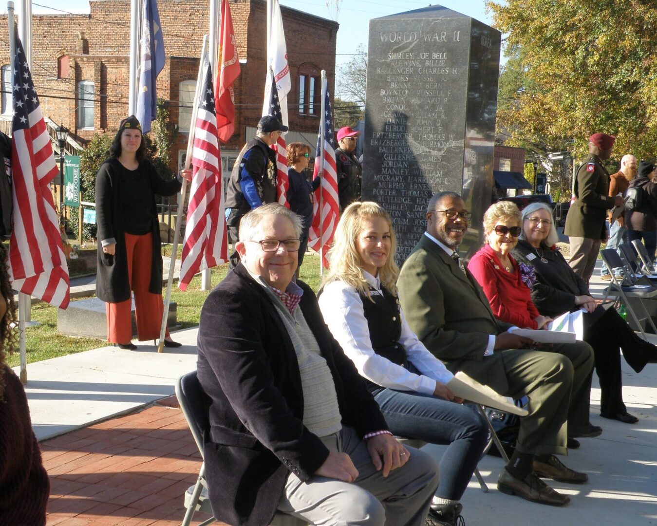 A group of people sitting on chairs in front of flags.