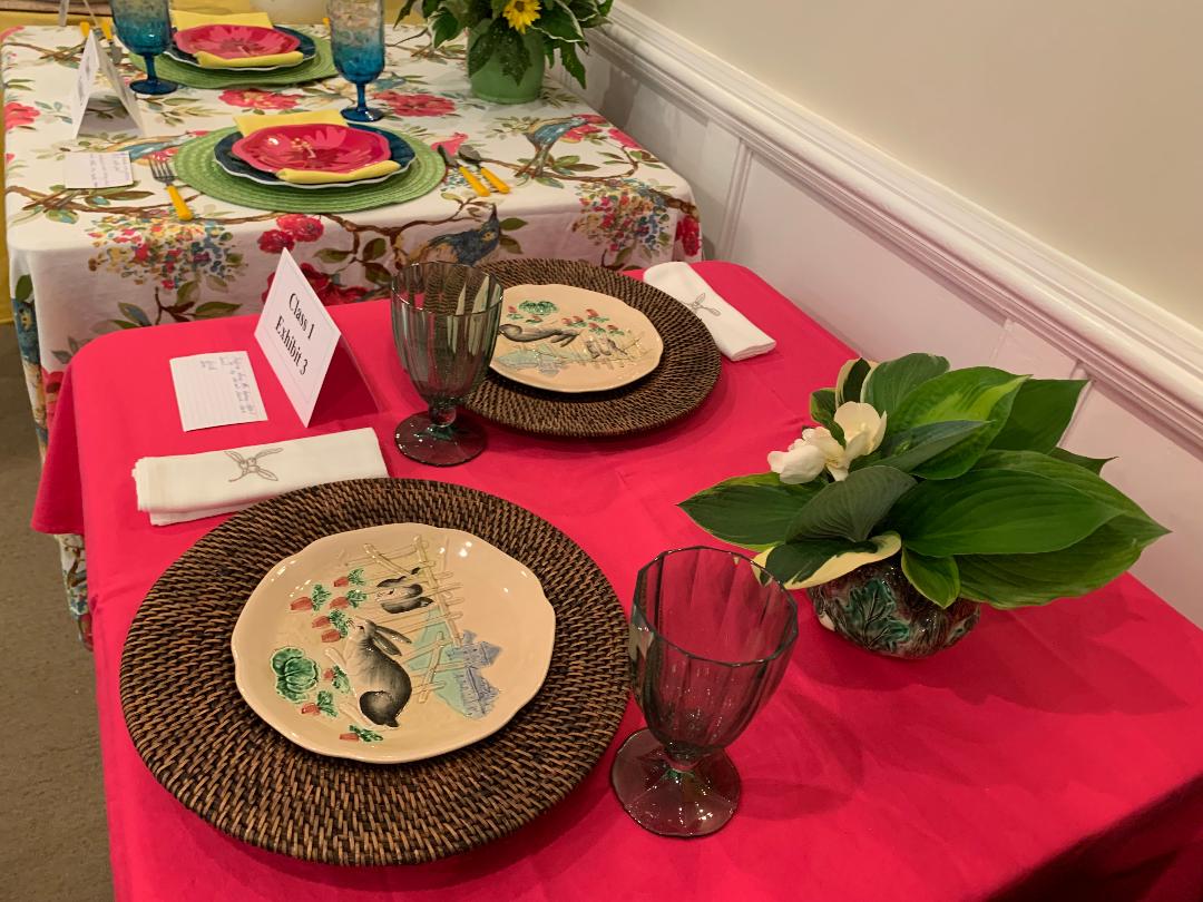 A table set with plates and glasses on top of red cloth.