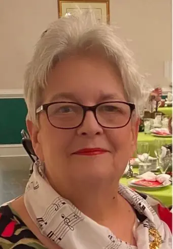 A woman with glasses and white hair.