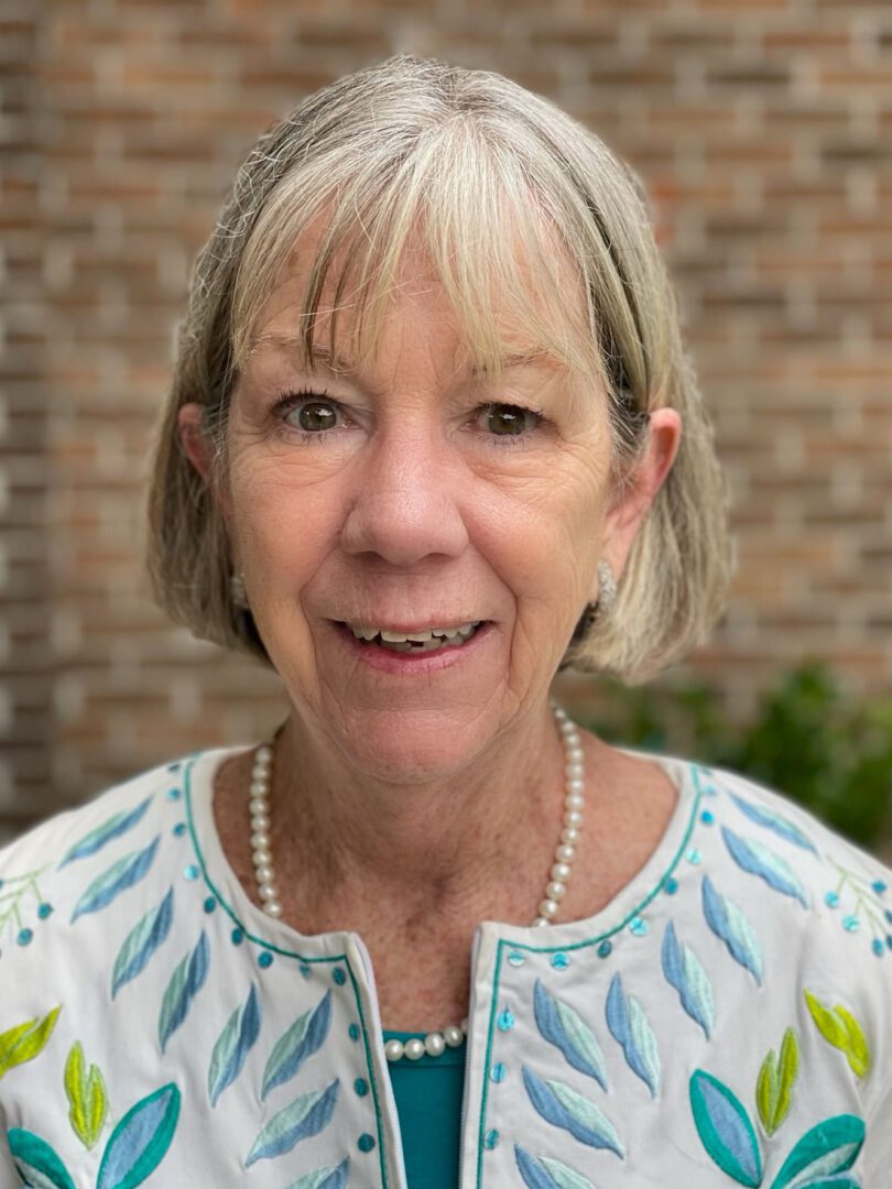 A woman with short blonde hair wearing a blue and white dress.