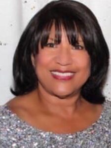 A woman with black hair and bangs wearing a silver dress.