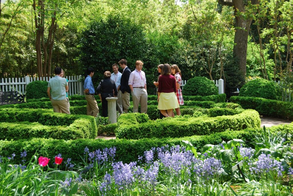 A group of people standing in the middle of a garden.