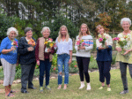 Group of women holding colorful flower bouquets.