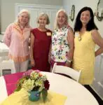 Four women posing by a decorated table.