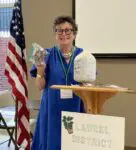 Woman holding bags, standing by podium.