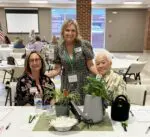 Three women smiling at a conference table.